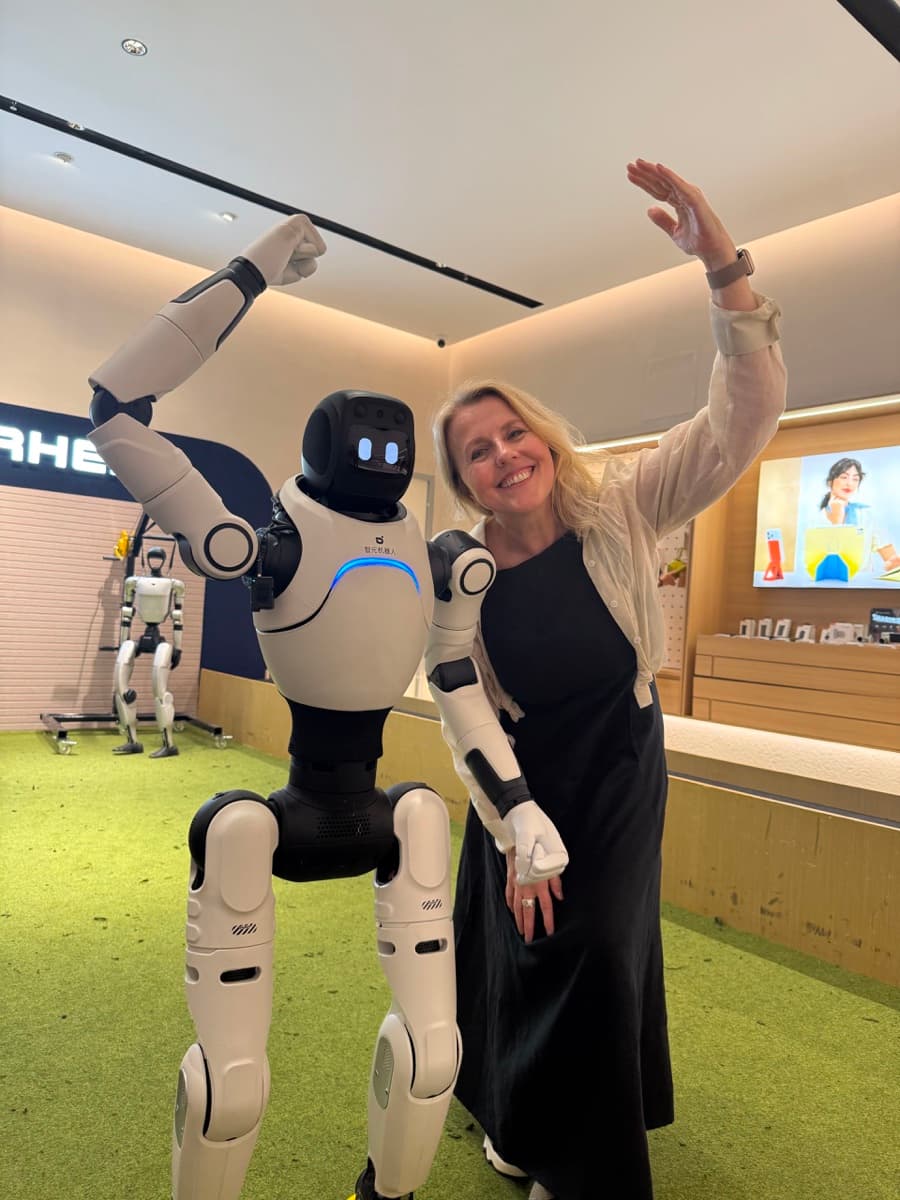 Foreign visitor posing with a humanoid robot at a Shenzhen showroom in 2026
