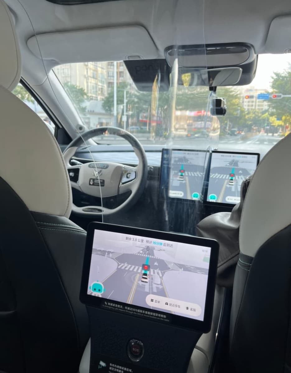 Inside a Pony.ai Level 4 robotaxi in Shenzhen showing the empty driver seat and the AI navigation tablet