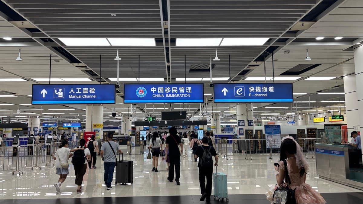 China Immigration hall at a Shenzhen border port — overhead signs mark the Manual Channel, China Immigration, and E-channel lanes